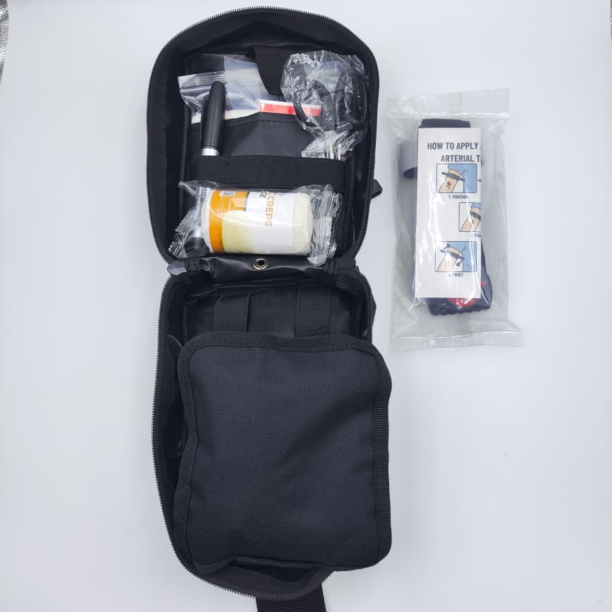Open compact first aid pouch with elastic crepe bandage, marker, trauma shears and arterial tourniquet accessory.